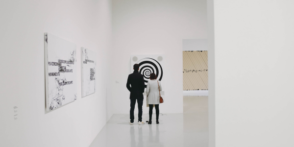 Two people standing in an art gallery, viewing a painting
